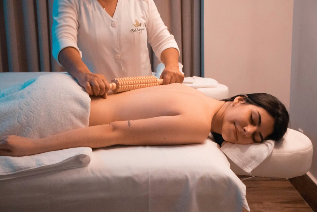 Woman receiving relaxing back massage therapy with wooden roller at spa