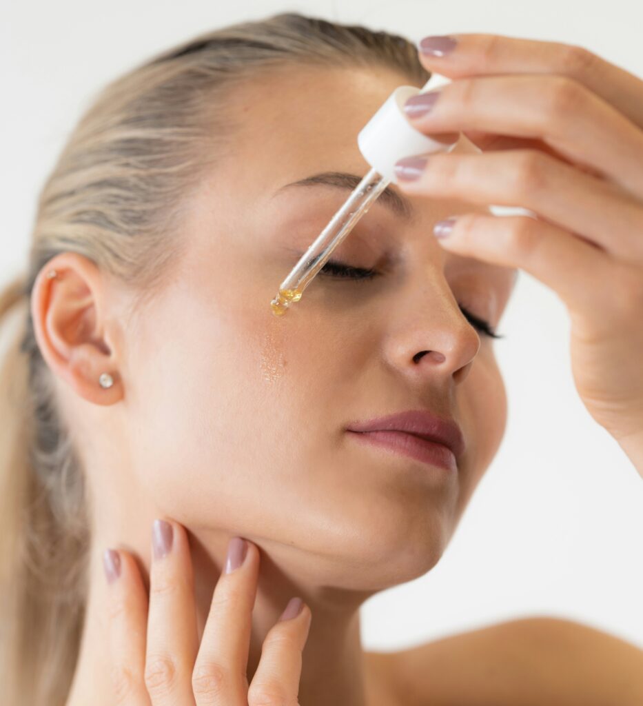 Woman applying nourishing face oil with dropper during skincare routine for glowing and hydrated skin