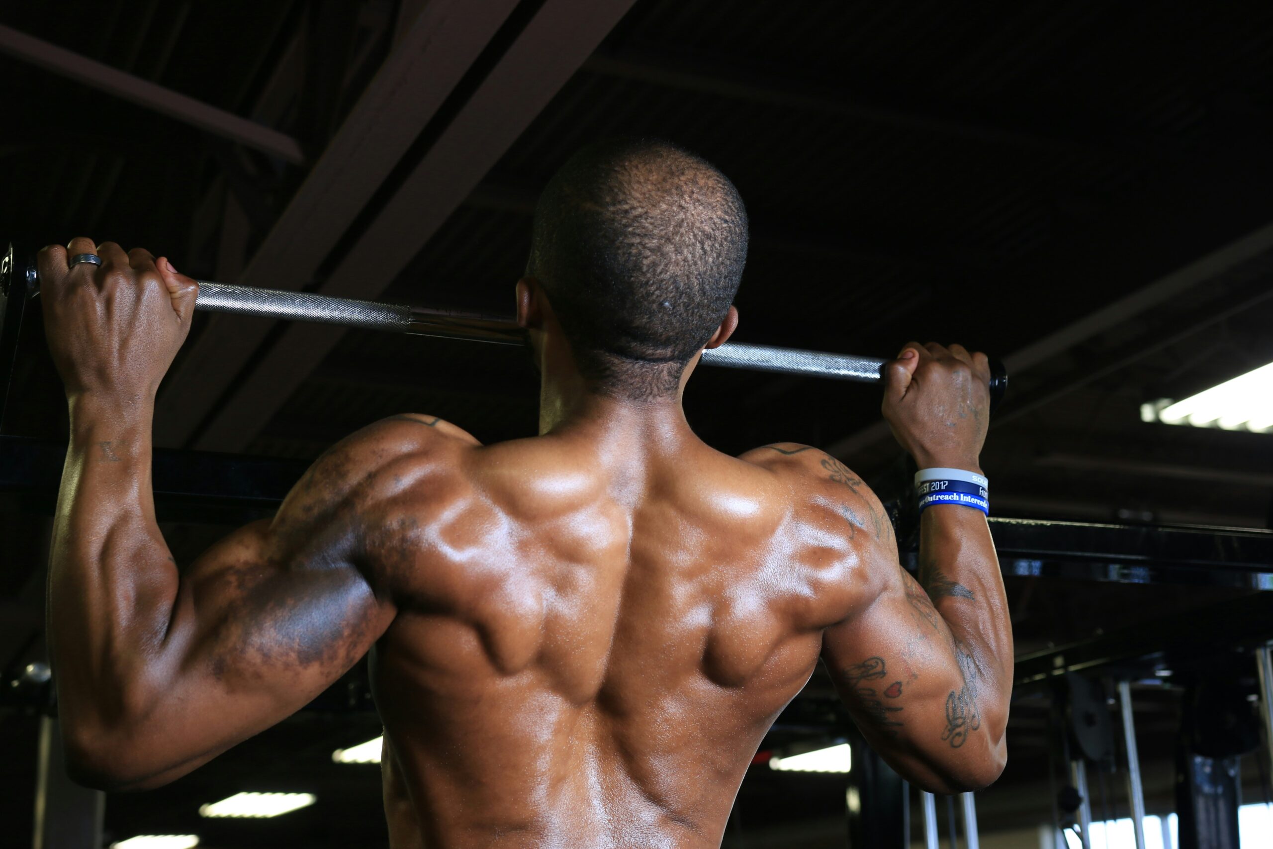 Fit man performing pull-ups in gym showcasing strong back muscles and upper body workout