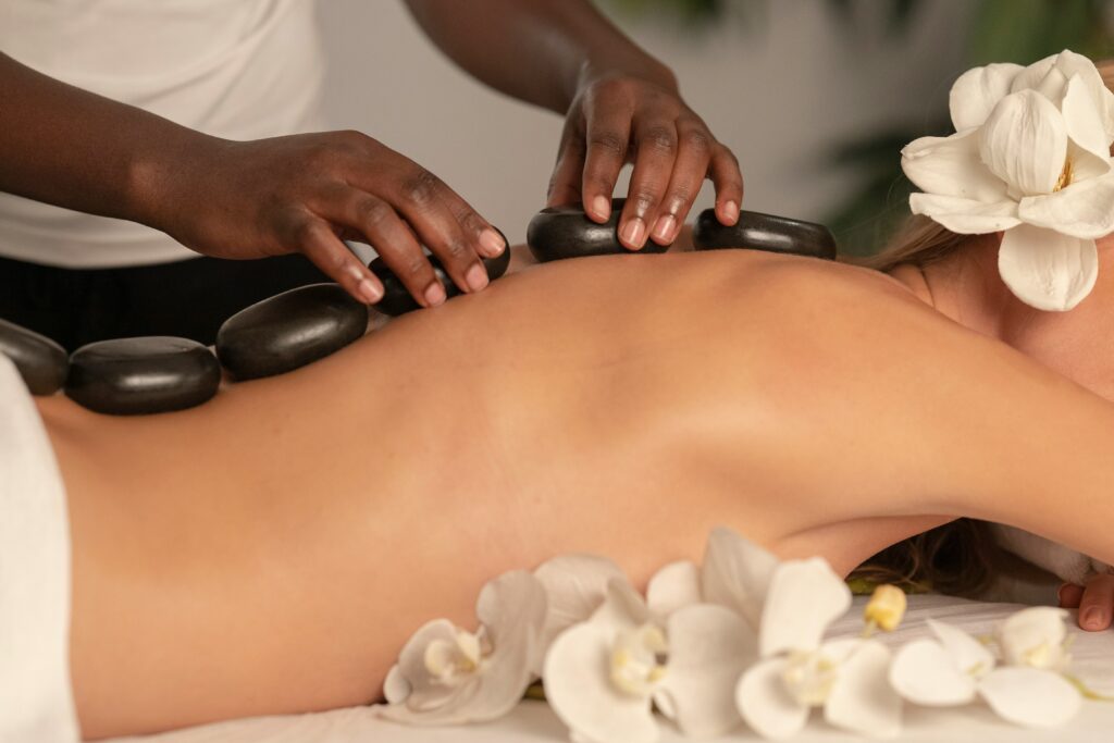 Hot stone massage therapy at a luxury spa with smooth black basalt stones placed on a woman's back for deep muscle relaxation and stress relief.