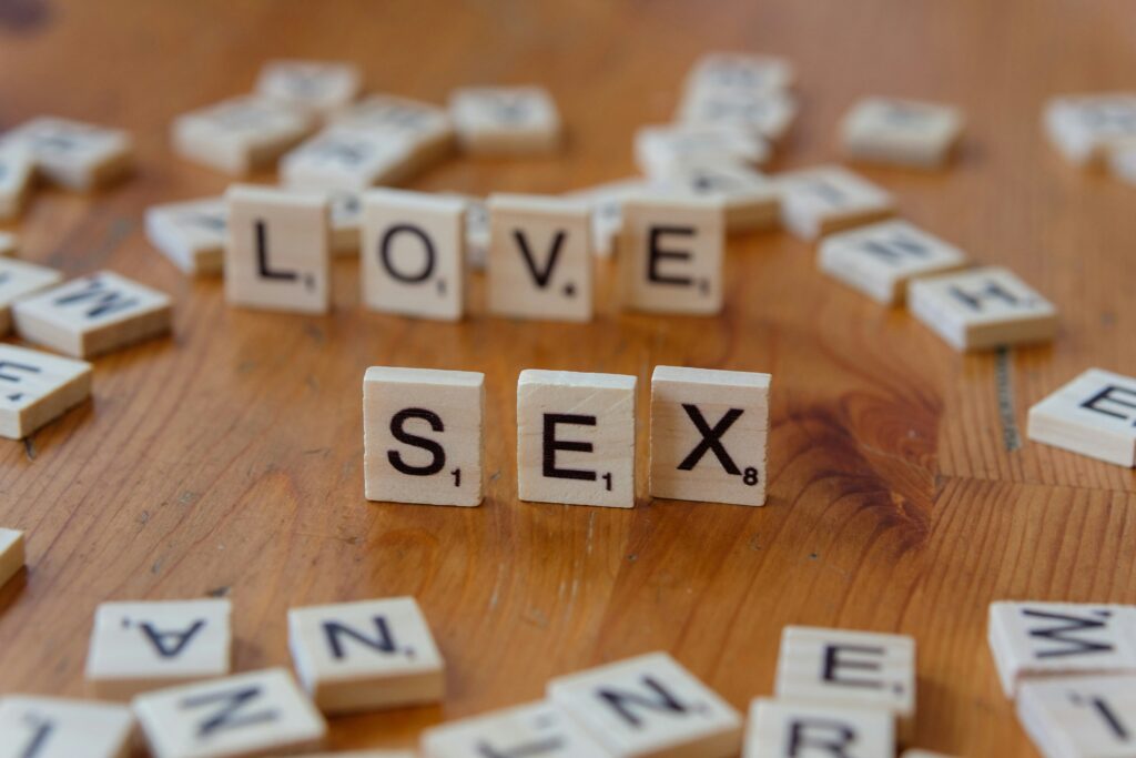Scrabble tiles spelling love and sex on a wooden table representing romantic relationships and intimacy